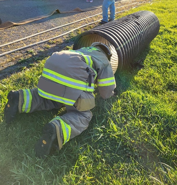 a young person dressed in firefighter gear practicing a safety drill